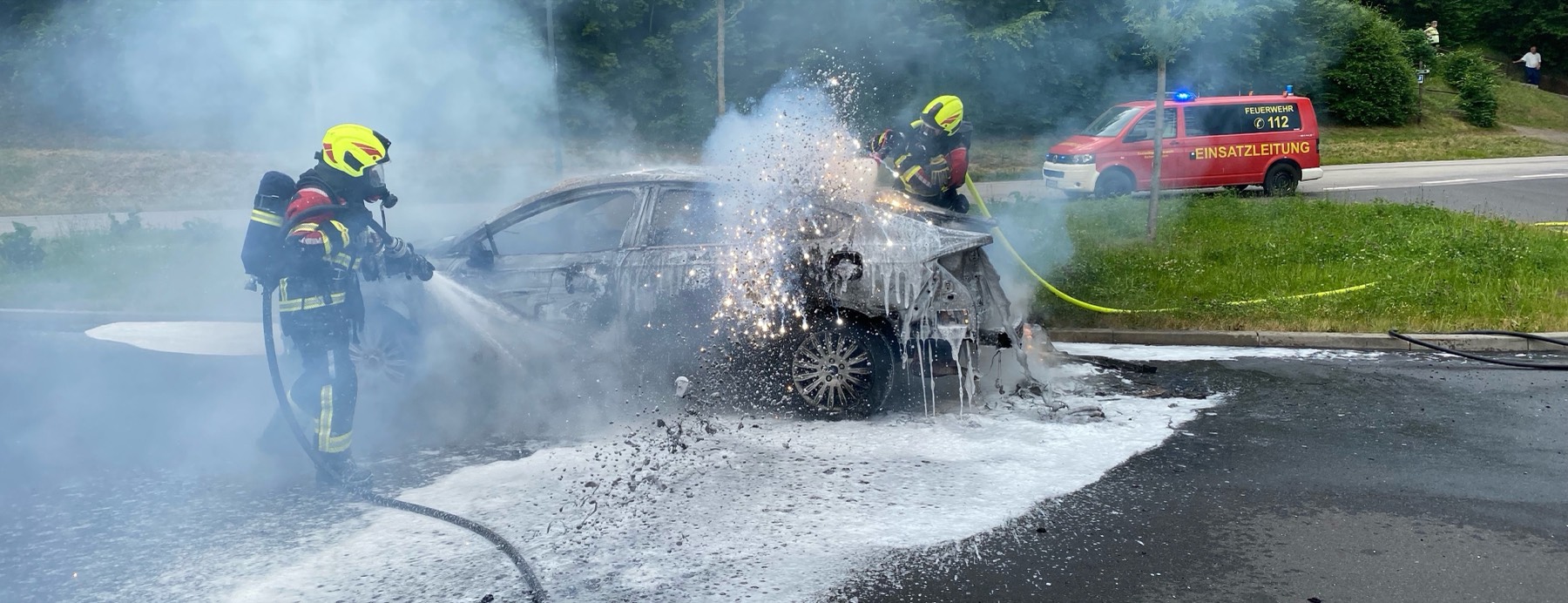 Zwei Einsatzkräfte der Feuerwehr Schmalkalden löschen einen Fahrzeugbrand mit Schaum