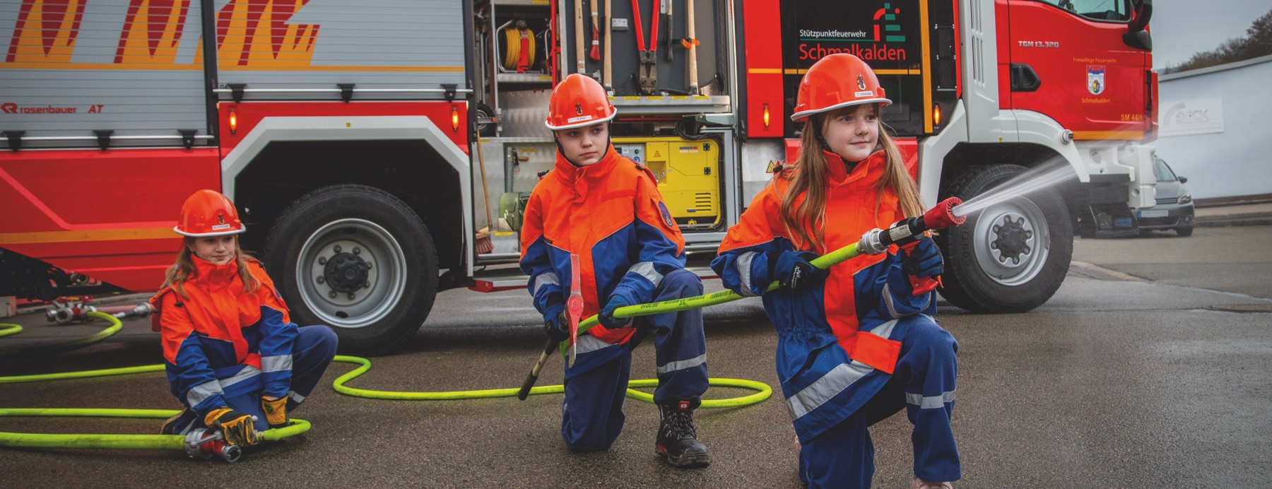 Mitglieder der Jugendfeuerwehr beim Löschangriff vor dem Hilfeleistungslöschgruppenfahrzeug